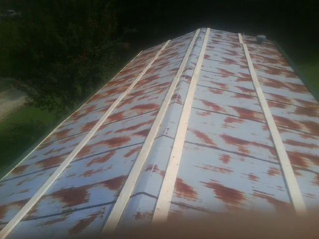 Rusted metal roof panels with new wood purlins before replacement — Storm Damage Roof Repair in Zearing by Roofing Brothers