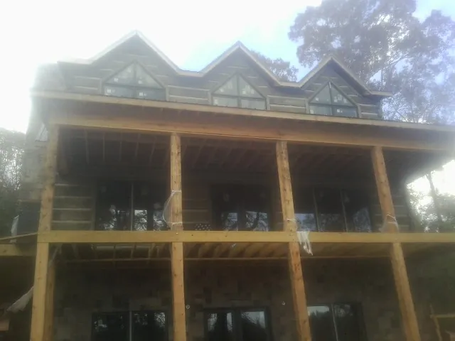 Dormers and porch framing on a large log home under construction — Roof Coating work by our crew in Zearing