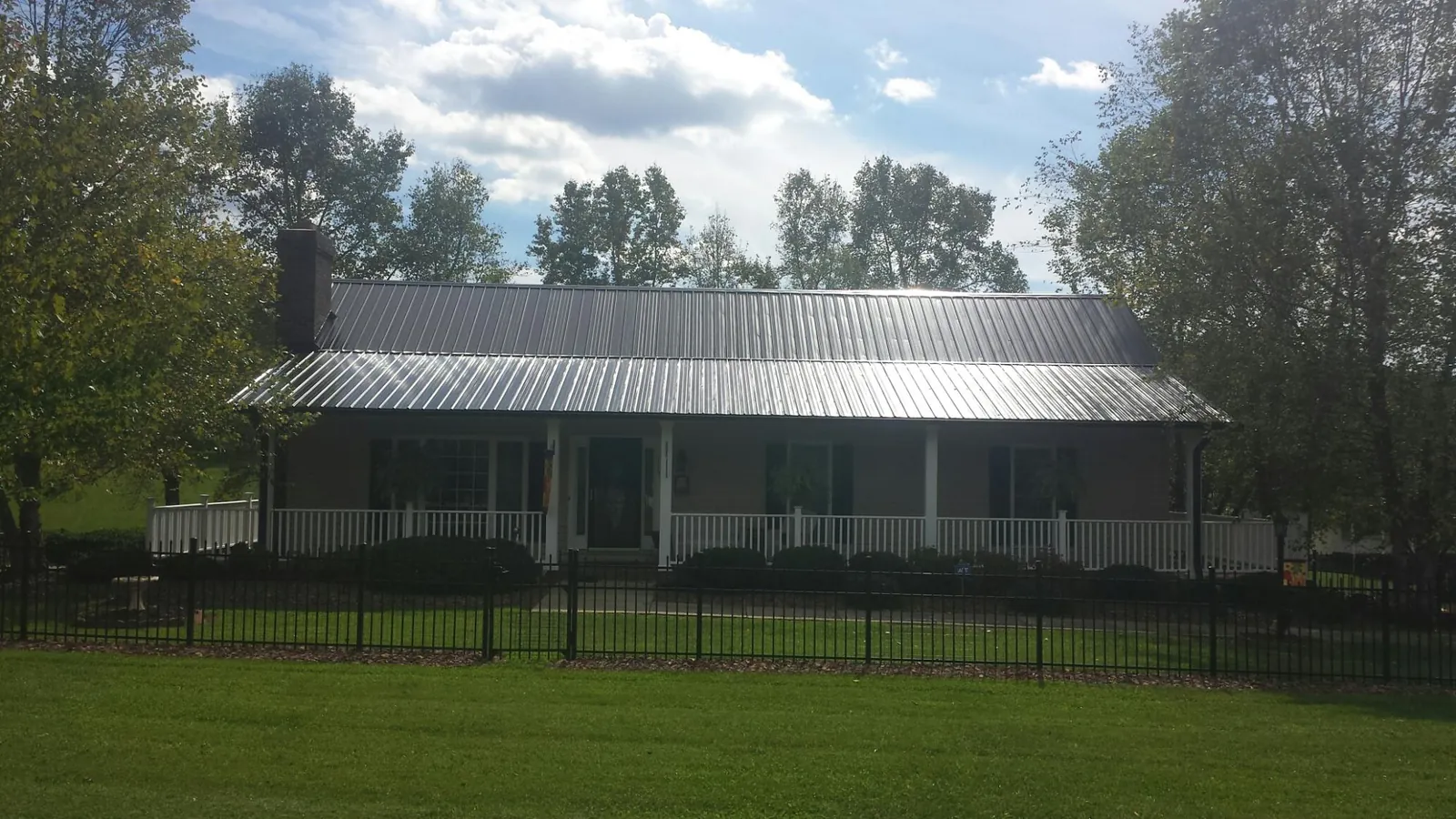 Gray metal roof on a brick ranch with a full width front porch — Gutter Guard Installation work by our crew in Zearing