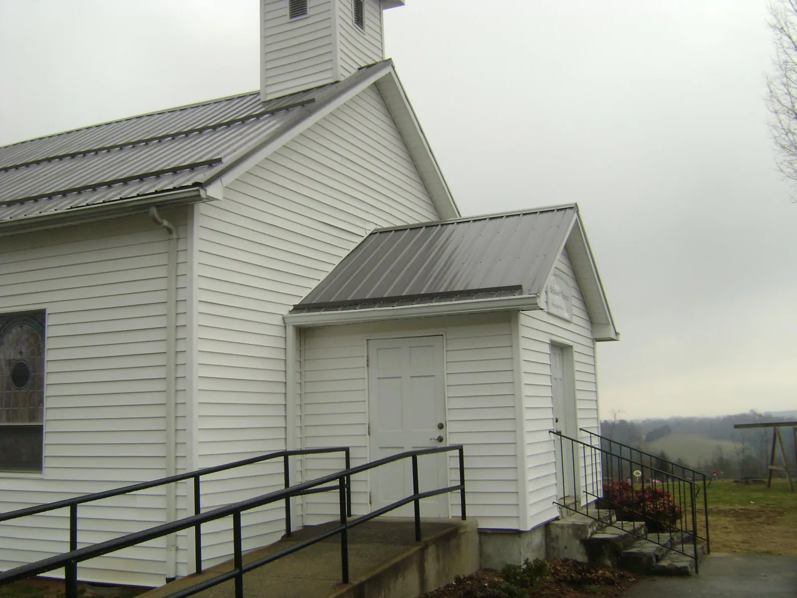 Gray metal roof on a white clapboard church with a steeple in Zearing